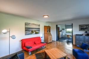 ein Wohnzimmer mit einem roten Stuhl und einem Tisch in der Unterkunft Breubergblick, Stylisches Apartment in Breuberg in Breuberg