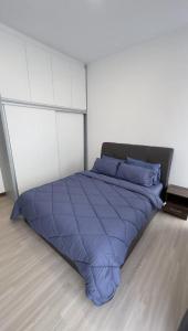 a bed with a blue comforter in a room at APARTMENTS @ PODIUM, KUCHING in Kuching