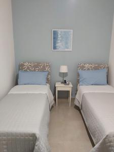 una stanza con due letti e un tavolo con una lampada di B&B Carpe Diem a Gravina di Catania