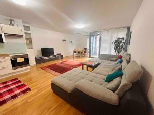 ein Wohnzimmer mit einem großen Sofa und einer Küche in der Unterkunft Comfortable living in our spacious home in Wien