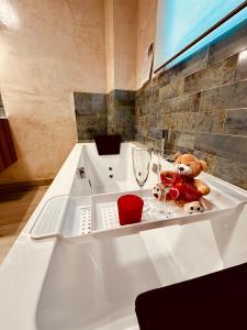 una vasca da bagno con un orsacchiotto e un bicchiere di vino di Cherry JACUZZI Apartment a Ronda