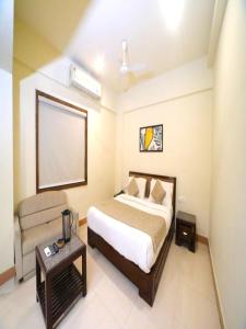 Habitación de hotel con cama y silla en Hotel Pine Tree, en Rajkot