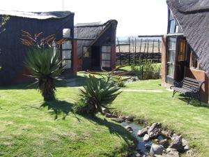 ein Haus mit einer Bank und einem Bach im Hof in der Unterkunft Hawane Resort in Mbabane