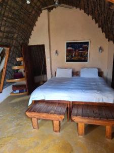 a bedroom with a bed with two wooden benches at Hawane Resort in Mbabane