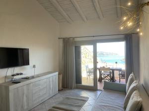 sala de estar con TV y puerta corredera de cristal en Punta Est Trilocale Splendida Vista Mare, en Capo Coda Cavallo