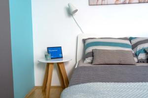 a bedroom with a bed and a table with a laptop on it at Tiffany Apartment in Novi Sad