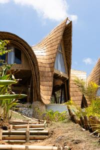 a building with a curved roof with windows and plants at Villa Grazia - Anima Eco Lodge -Ville Lussuose con Piscina Vista Mare in Selong Belanak