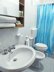 a bathroom with a sink and a toilet and a blue shower curtain at Holiday home Mennulita in Lipari