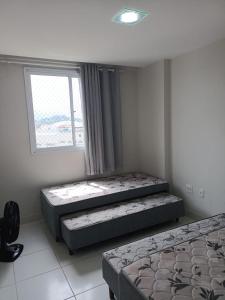 two beds in a room with a window at Apartamento 2 quartos Prédio frente Para o Mar início da Praia do Morro in Guarapari