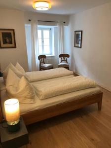 a large bed in a room with a lamp and two chairs at Schön wohnen beim Stift in Melk