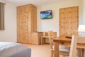 a bedroom with a bed and a table and a tv at Bachäckerhof - Nichtraucherhotel- in Ravensburg