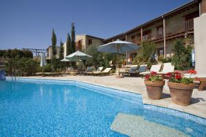 a swimming pool with chairs and umbrellas next to a building at Eveleos Country House in Tochni