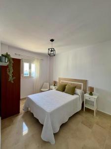 a bedroom with a large white bed and two tables at Apartamento Alto Castillo, centro histórico con garaje y WiFi in Sanlúcar de Barrameda