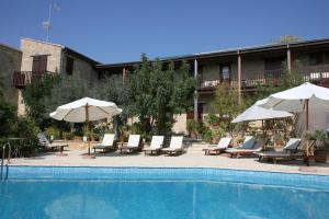 a pool with chairs and umbrellas next to a building at Eveleos Country House in Tochni