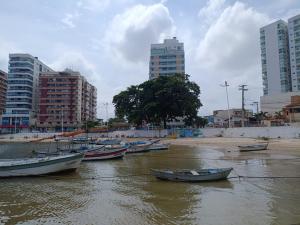 a group of boats in the water in a city at Apartamento Pé na Areia, Wi-Fi e Garagem Privativa início da Praia do Morro in Guarapari