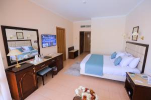 um quarto de hotel com uma cama e uma secretária em Sea Star Beau Rivage Hotel em Hurghada