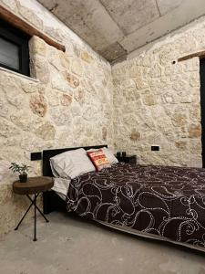a bedroom with a bed in a stone wall at The Hermitage: Timeless charm&Beach&History nearby in Yenibosazici