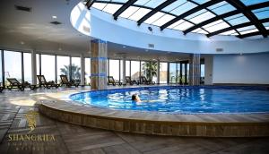 a person swimming in a large pool in a building at Orbi City Beach Hotel Batumi in Batumi