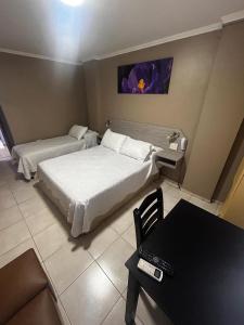Habitación de hotel con 2 camas y mesa en Hotel Everest en Córdoba