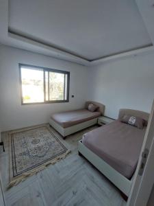a bedroom with two beds and a window and a rug at The Wave residence Chott Meriam Sousse in El Ahmar
