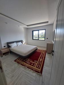 a white bedroom with a bed and a rug at The Wave residence Chott Meriam Sousse in El Ahmar