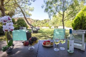 uma mesa com copos de vinho e fruta em Alghero Villa Mistral per 7 persone Terrazza BBQ AC WiFi em Alghero