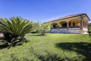 uma casa com uma palmeira em frente a um quintal em Alghero Villa Mistral per 7 persone Terrazza BBQ AC WiFi em Alghero