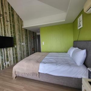 a bedroom with a bed with a green wall at Glagla Pension in Seogwipo