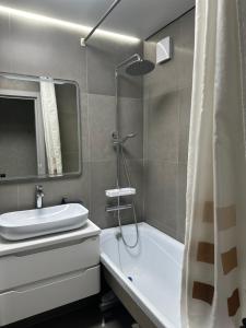 a bathroom with a sink and a tub and a shower at Однокомнатная квартира в центре города in Uralsk
