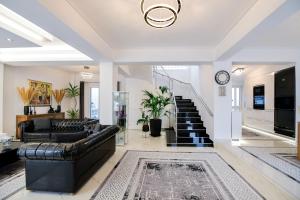 a living room with black leather furniture and a staircase at Beach Blue Villa in Korinthos