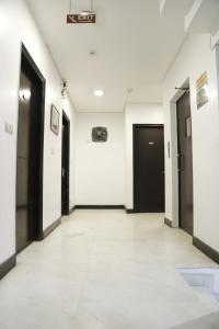 un pasillo vacío con puertas negras y paredes blancas en Hotel Sweet Home Lodge - 2 min from New Delhi Railway Station, en Nueva Delhi