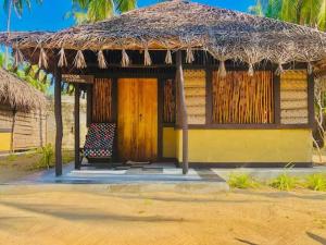 una cabaña con un banco y un techo de paja en LANKATHILAKA KITESURFING HOLIDAY RESORT en Kalpitiya