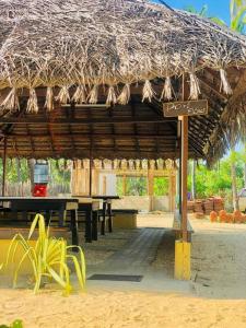 un restaurante con mesa y techo de paja en LANKATHILAKA KITESURFING HOLIDAY RESORT, en Kalpitiya