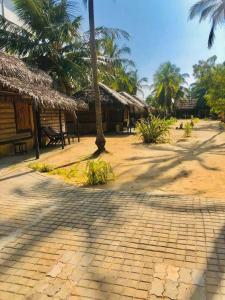 a resort with straw huts and palm trees at LANKATHILAKA KITESURFING HOLIDAY RESORT in Kalpitiya