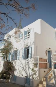 a white building with blue windows and stairs at NISOS Home Stay in Mikonos