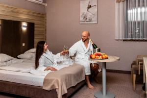 un hombre y una mujer sentados en una cama con copas de vino en Hotel Aquarius Restaurant Wellness Spa, en Ciechocinek