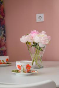 a vase of pink flowers and a cup on a table at Солнечная квартира с видом на горы in Almaty