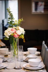 una mesa con platos y un jarrón de flores. en New, modern 4 bed, 3 bath house ,free parking en Oxford