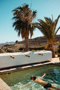 un hombre en una piscina en el desierto con palmeras en Cortijo Los Malenos, en Agua Amarga