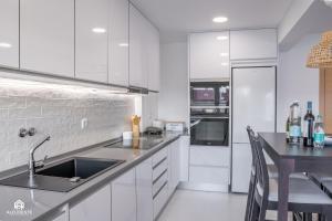 a white kitchen with a sink and a counter at Navio Beach Apartment Santa Cruz in Santa Cruz