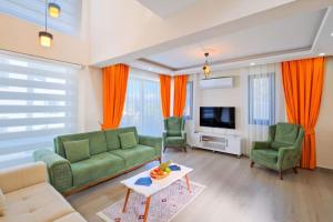 a living room with a couch and two chairs and a tv at Villa Simge 3+1 Ölüdeniz in Fethiye