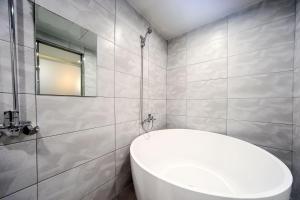La salle de bains est pourvue d'une baignoire blanche et d'un miroir. dans l'établissement ON:NA Hotel, à Busan