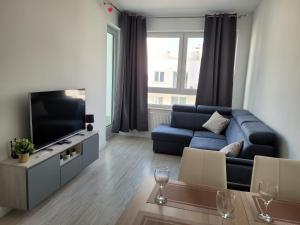 uma sala de estar com um sofá azul e uma televisão em Cozy Appartment with Gym, free Parking, Ursus em Varsóvia