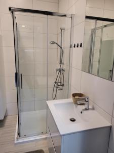 ein weißes Bad mit einer Dusche und einem Waschbecken in der Unterkunft Cozy Appartment with Gym, free Parking, Ursus in Warschau