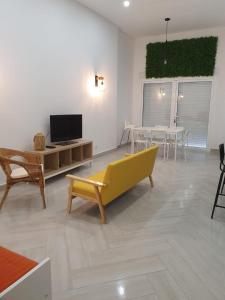 uma sala de estar com um sofá amarelo e uma televisão em Coconut Monte Gordo em Monte Gordo