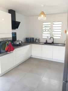 a white kitchen with white cabinets and a sink at Ti kaz Salazie 1 in Salazie