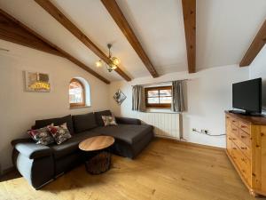 un soggiorno con divano nero e TV di Appartements Binderhof a Kirchdorf in Tirol