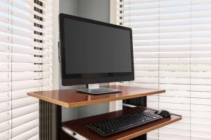 a computer monitor and a keyboard and mouse on a desk at Days Inn by Wyndham Cocoa Beach Port Canaveral in Cocoa Beach