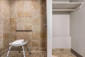 a shower with a chair in a bathroom at Days Inn by Wyndham Cocoa Beach Port Canaveral in Cocoa Beach