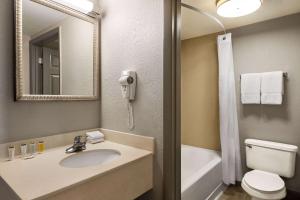 uma casa de banho com um lavatório, um WC e um espelho. em Days Inn by Wyndham Cocoa Beach Port Canaveral em Cocoa Beach